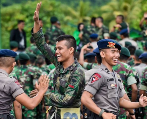 Personel TNI dan Polri berseragam saling berinteraksi dengan semangat kebersamaan di ruang terbuka hijau.